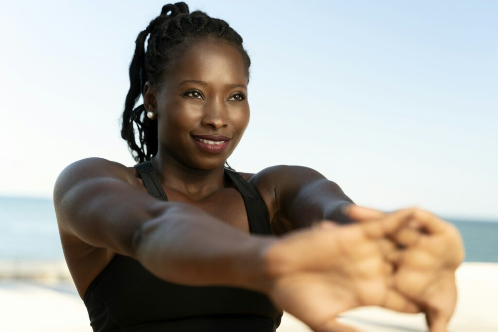 Purposeful fitness woman stretching hands at the beach